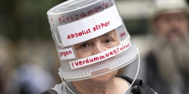 Ein Demonstrant geht mit einem Plastikeimer über dem Kopf durch Berlin-Charlottenburg und liest am Sonntag, den 1.  (Fabian Sommer / dpa via AP)