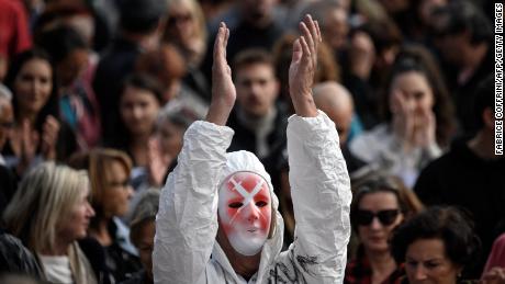 Ein Demonstrant, der eine Spritzenmaske und einen vollen Schutzanzug trägt, applaudiert am 9. Oktober 2021 in Genf.