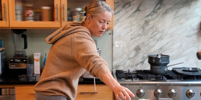 Joy Klineberg wirft eine Zitronenschale in eine Plastiktüte, um sie zum Kompostieren zu verwenden, während sie am Dienstag, den 30. November 2021, in ihrem Haus in Davis, Kalifornien, ein Familienessen kocht.