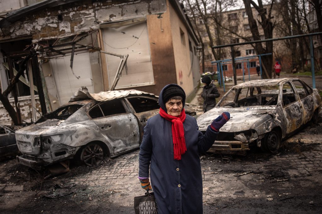Eine alte Ukrainerin vor einem beschädigten Gebäude