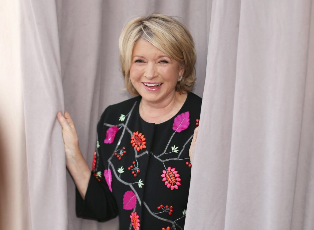 Martha Stewart lächelt und hält Vorhänge