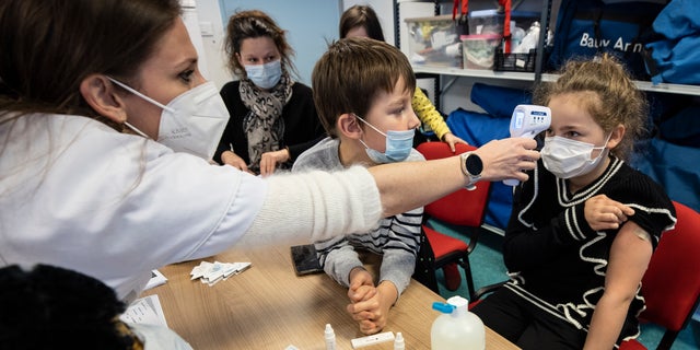 Ein medizinischer Mitarbeiter misst am Dienstag, 21. Dezember 2021, die Temperatur eines Kindes in einem Impfzentrum in Sélestat, Ostfrankreich (AP Photo / Jean-Francois Badias)