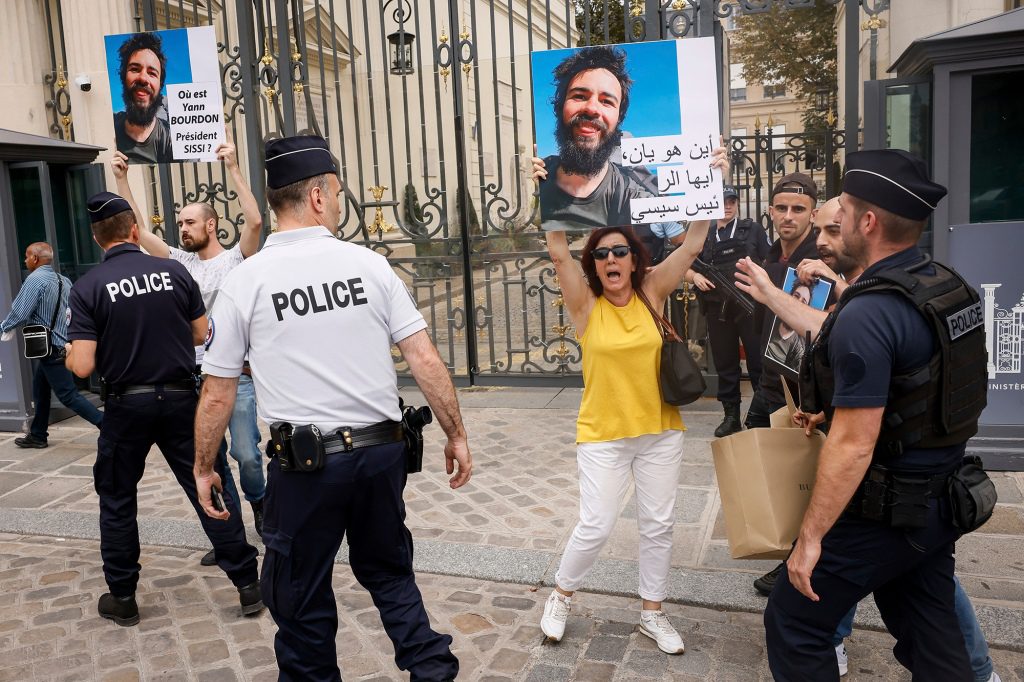 Die Familie und Freunde des Studenten standen auf einem Pariser Bürgersteig und hielten Schilder hoch, auf denen stand: 